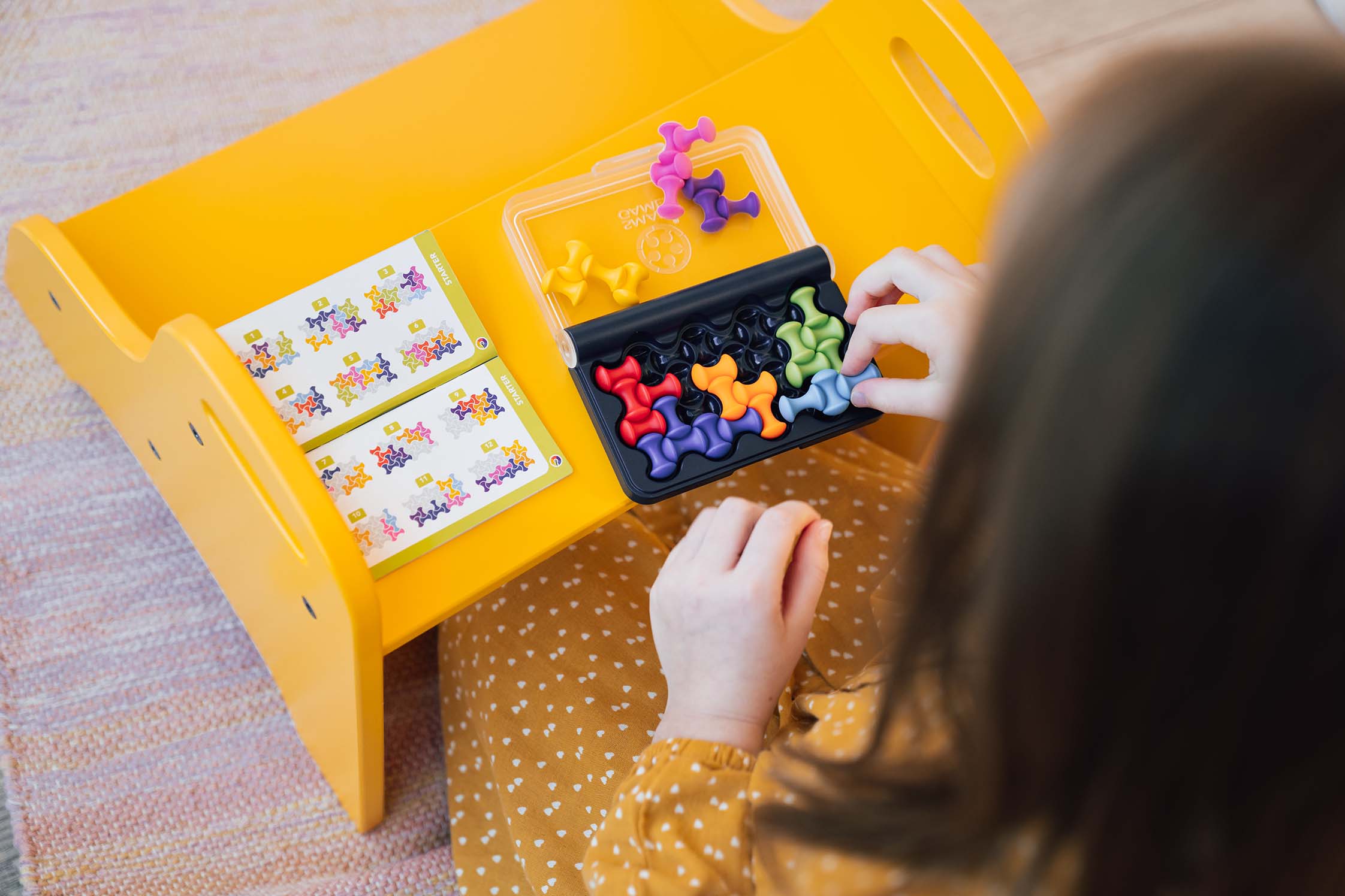 A child solving the puzzle beside the printed solution booklet